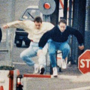 Two East Berliners jump across border barriers on the Eastern side of border checkpoint at Chaussee Street in Berlin in April of 1989. They were stopped by gun wielding East German border guards and arrested while trying to escape into West Berlin. People in the foreground, still in East Berlin, wait for permits to visit the West.