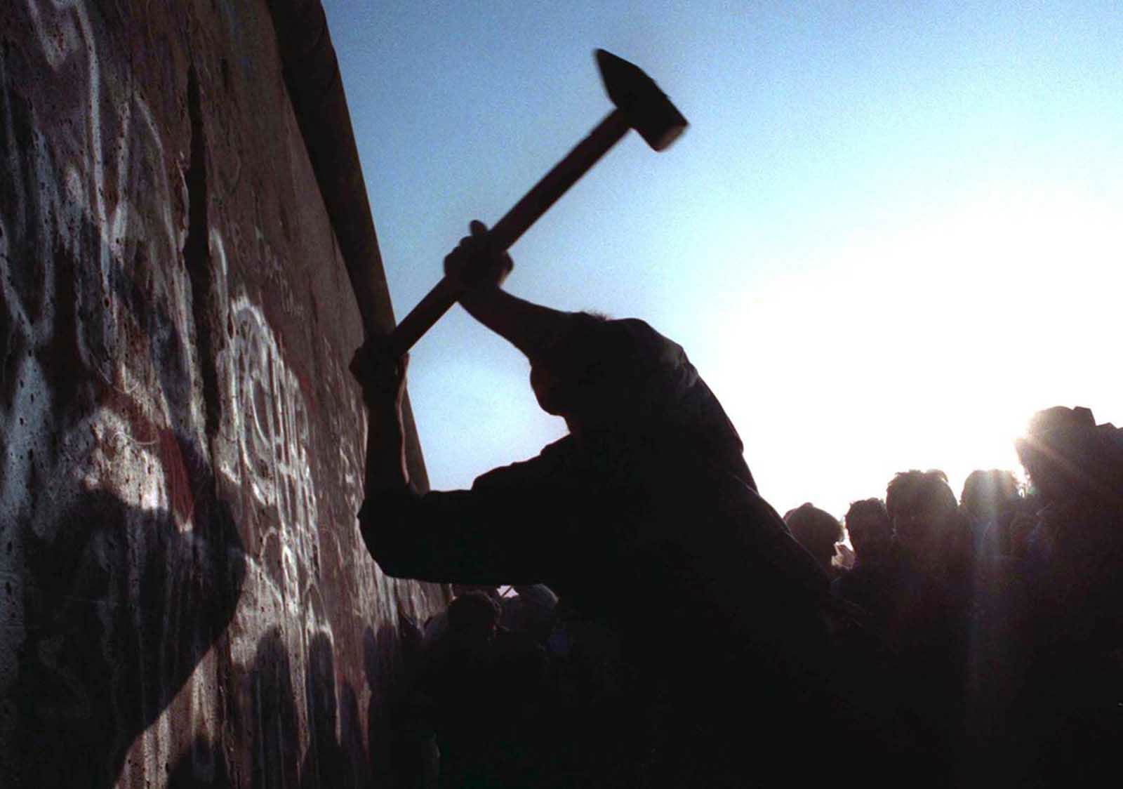A man hammers away at the Berlin Wall on November 12, 1989 as the border barrier between East and West Germany was torn down.