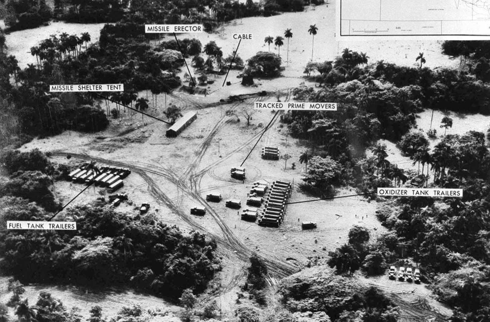 Evidence presented by the U.S. Department of Defense, of Soviet missiles in Cuba. This low level photo, made October 23, 1962, of the medium range ballistic missile site under construction at Cuba’s San Cristobal area. A line of oxidizer trailers is at center. Added since October 14, the site was earlier photographed, are fuel trailers, a missile shelter tent, and equipment. The missile erector now lies under canvas cover. Evident also are extensive vehicle tracks and the construction of cable lines to control areas.
